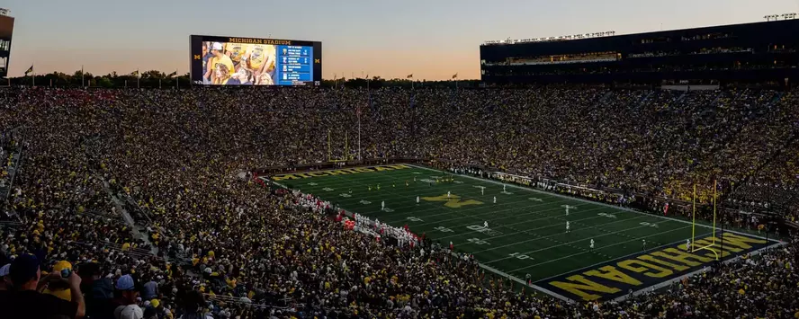 Michigan Stadium with Scoreboard and fans in the stadium at dusk