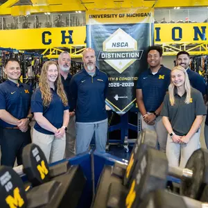 Strength and Conditioning Staff Poses with NCSA College Program of Distinction Banner