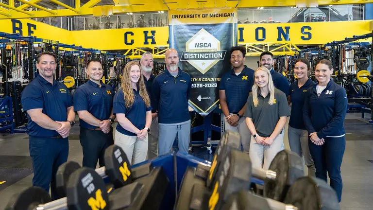 Strength and Conditioning Staff Poses with NCSA College Program of Distinction Banner