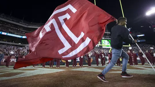 Image of a cheerleader carrying the Templel flag