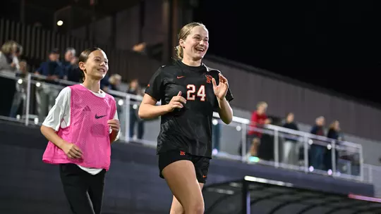 Stella Monberg runs onto the field alongside a ball kid