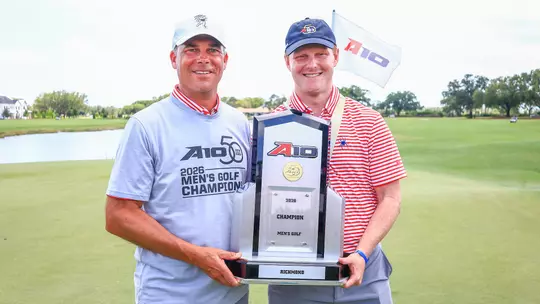Adam Decker and Cole Ekert pose with the A-10 trophy on the green at Evermore Resort