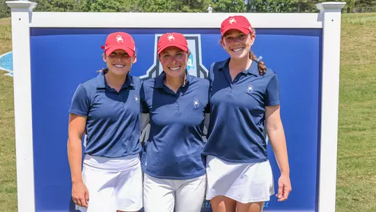 Calle Barlow poses with two Spider golfers in front of the NCAA regionals sign