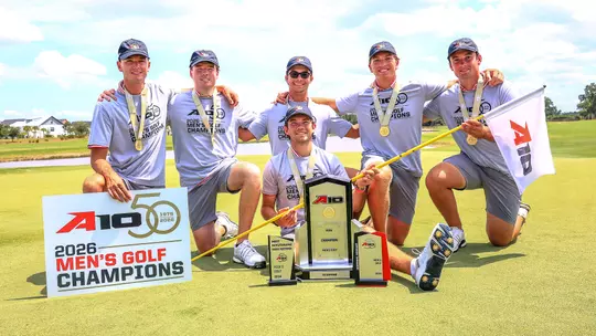 Men's golf poses on the green after winning the A-10 Championship