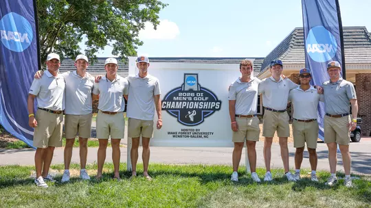 The men's golf team poses in front of an NCAA Regional sign at Bermuda Run Country Club