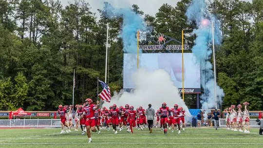 Football team running out of the tunnel during a game at Robins Stadium in 2025