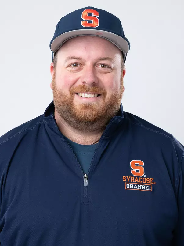 Syracuse field hockey assistant coach Sam Brown head shot. He's wearing a blue pullover with Syracuse University branding and a blue hat all on a white background.
