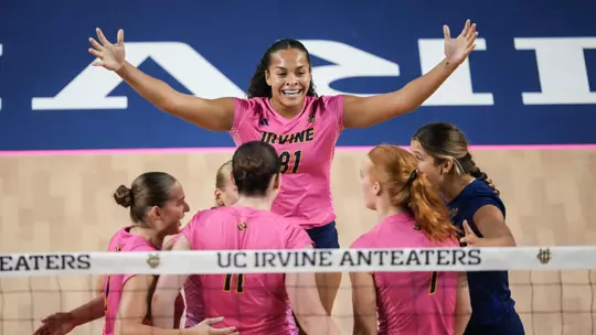 Memphis Burnett raises both arms as she celebrates a point with her teammates in an NCAA women's volleyball match.