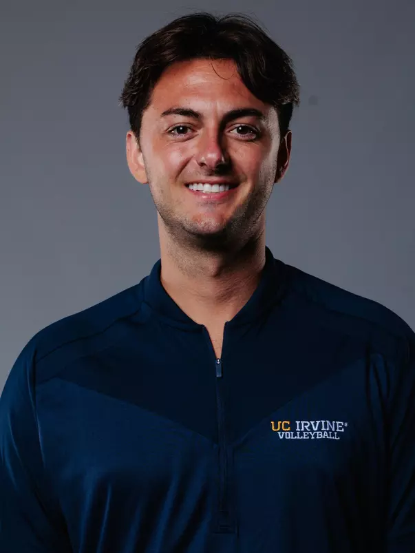 Assistant coach Trevor Briggs poses for a head shot in a blue quarter zip with the text UC Irvine Volleyball