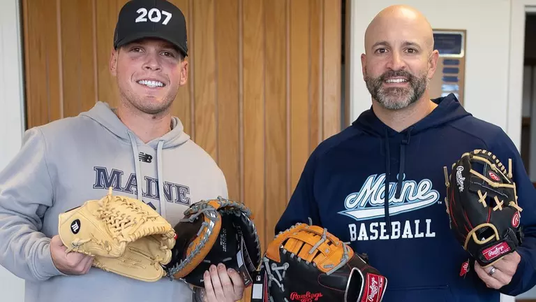 Head Coach Nick Derba and former maine baseball player Connor Goodman posing with baseball gloves.