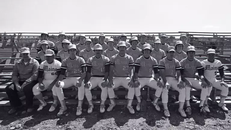 A team photo of the 1976 Maine Baseball sitting on the bleachers.