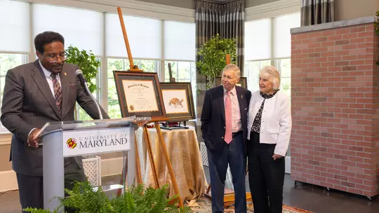 President Darryll Pines presents legendary Voice of the Terps Johnny Holliday with an honorary degree.