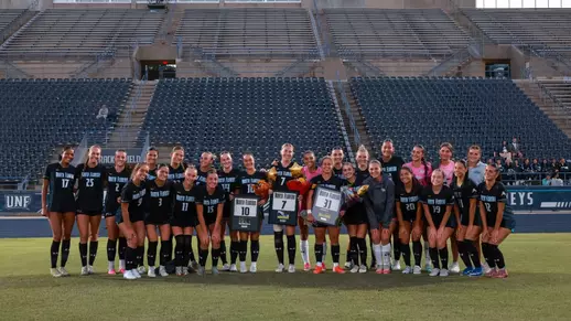 UNF Women's soccer team celebrates senior night by posing for a photo.