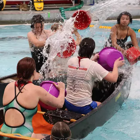 UVM students in a canoe in the pool throwing water on each other