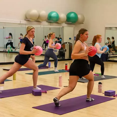UVM student holding exercise balls in a group fitness class