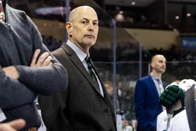 Photo: bsubeavers.com Tom Serratore stands behind the bench during a game, watching the action on the ice while assistant coaches and players