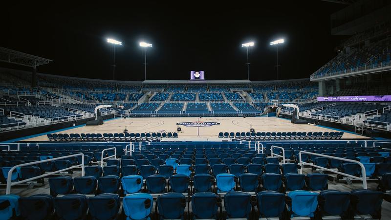 The Lindner Family Tennis Center center court covered in a basketball court under the stadium lights.