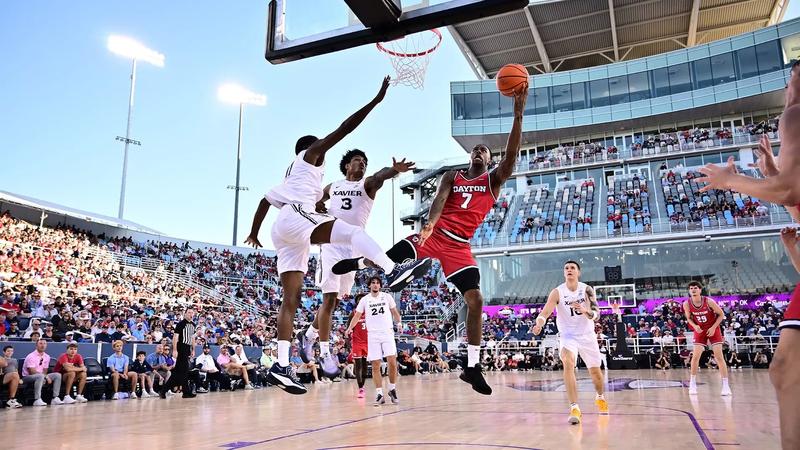 Zaide Lowery goes up for a layup on the right as two Xavier players go up on the left in defense. He is wearing a red uniform, while the Xavier players are in white.