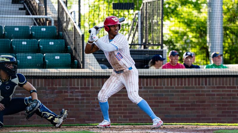 Michael Smith Jr. stands in the right-handed batter's box, waiting for the pitch. He is wearing a white pinstripe uniform and a red helmet.