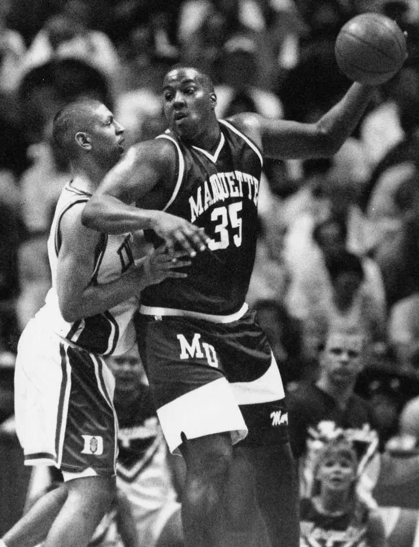 Marquette player Damon Key looks to pass the ball while being blocked by a defender, 1991-1994.
