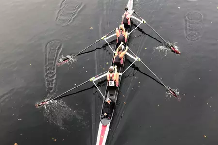 An Eagles four-person boat rows under a bridge.