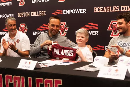 Nicholas Palamidis holds up a custom BC jersey, next to head coach Jeff Hafley, after signing with BC football through Team IMPACT.