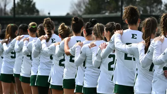 Members of the lacrosse team place their left hands on their teammate's shoulder during the playing of the national anthem
