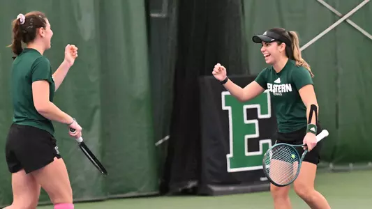Regina Mendez Carreno (right) fist pumps and smiles as she walks toward playing partner Iva Daneva after winning a point against Cleveland State