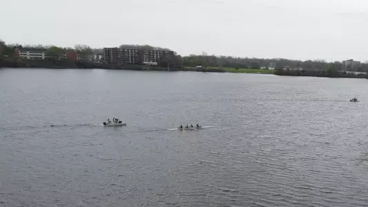 A 1920 x 1080 aerial image depicting an Eastern Michigan University women's fours boat on the stunning waters of the EMU Rowing Course at Ford Lake