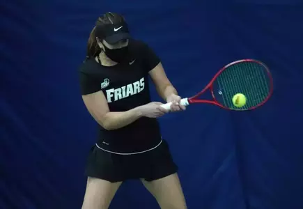 Friar women's tennis player hitting the ball backhand during a 2021 indoor match.