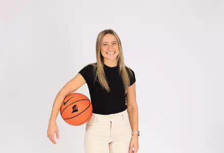 Biancan Lindberg men's basketball academic coordinator poses with basketball 