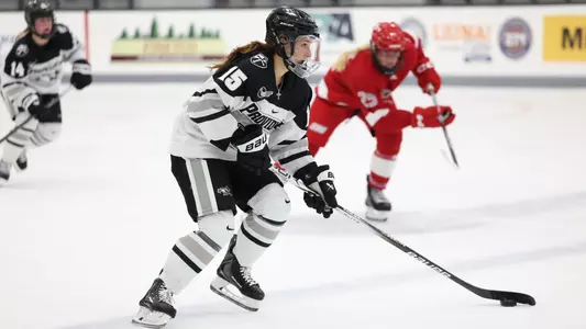 Women's ice hockey player Kayla Kutes skating up ice with the puck