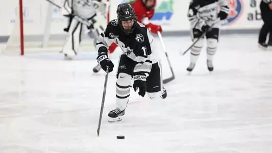 Women's ice hockey player Megane Quirion skating up ice with the puck during a game