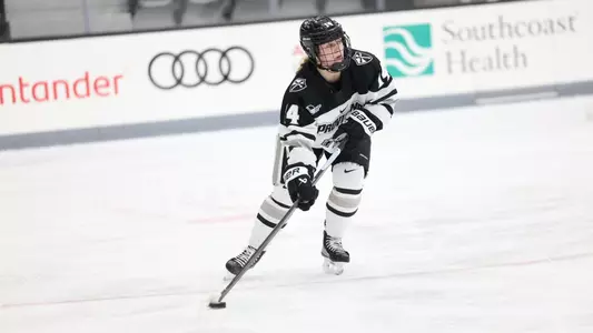 Women's ice hockey player Josie Lang skating up ice with the puck
