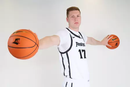 Peteris Pinnis men's Basketball player is posing during photoshoot carrying one basketball in each hand and looking at the camera.