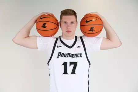 Peteris Pinnis men's basketball player is posing with two basketballs in each arm while he looking at the camera during photoshoot.