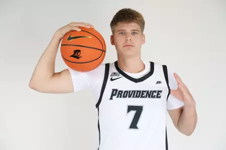 Stefan Vaaks men's Basketball player is pictured with a basketball on his right arm and his left thumb tucked under his jersey in their photoshoot.