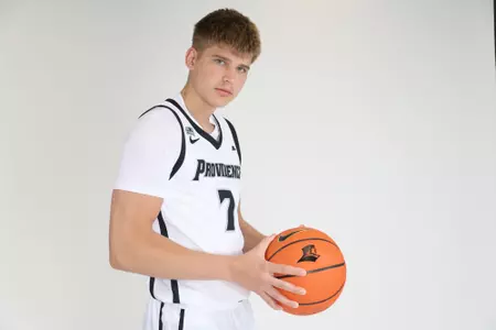 Stefan Vaaks men's Basketball player poses to the side while holding the basketball and looking at the camera during their photoshoot.
