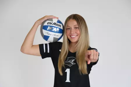 Miller McDonald poses by holding the volleyball in her right arm and pointing at the camera with her left arm during team photoshoot for pre-season 2025 photos.
