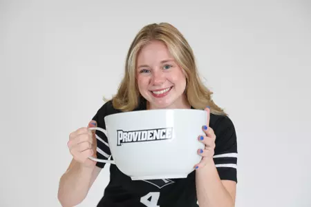 Addy Frye poses with a Providence College big mug and smiles at the camera during team photoshoot for pre-season 2025 photos.