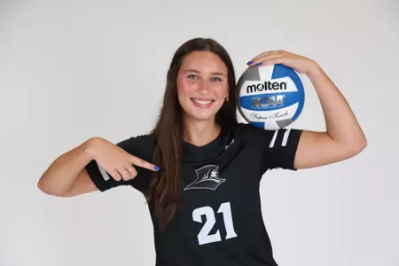 Sophia Adkins holds the ball in her left arm while she points at her jersey with her right hand during team photoshoot for pre-season 2025 photos.