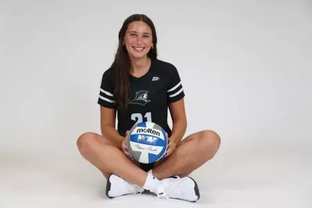 Sophia Adkins sits criss cross on the ground with the volleyball during team photoshoot for pre-season 2025 photos.