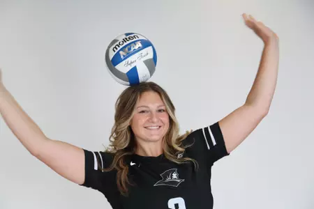 Audrey Kocon poses with the volleyball placed on top of her head and both hands in the air during team photoshoot for pre-season 2025 photos. 