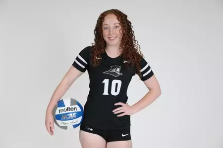 Morgan Martin is pictured holding a volleyball with her right hand at her hip and smiles at the camera during team photoshoot for pre-season 2025 photos.