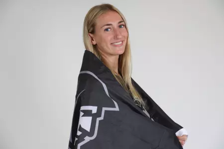 Fielding Mayhugh poses with the Providence College flag wrapped around her while she smiles at the camera during team photoshoot for pre-season 2025 photos.