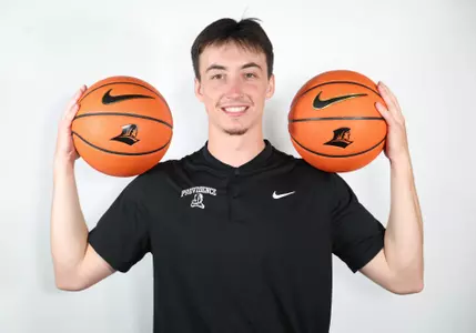 Thibaut Tagnon, men's basketball grad manager, poses with a basketball on each shoulder on Aug. 29, 2025.