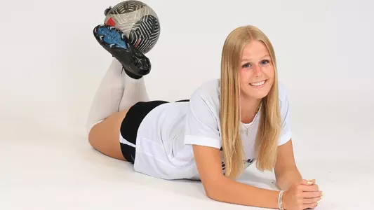 Women's soccer player Mara Batchen poses for a photo with a ball between her legs during a preseason photoshoot in 2025