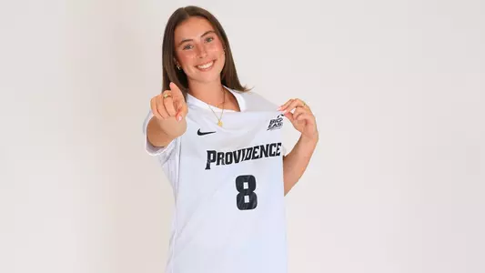 Women's soccer player Colleen Casey poses for a photo pointing at the camera and holding her jersey out during a preseason photoshoot in 2025