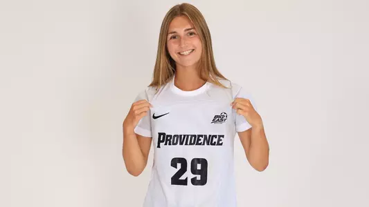 Women's soccer player Ahnna Faust poses for a photo holding her jersey out during a preseason photoshoot in 2025
