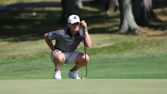 Men's golf player Evan Buddenhagen looking at the read on the green